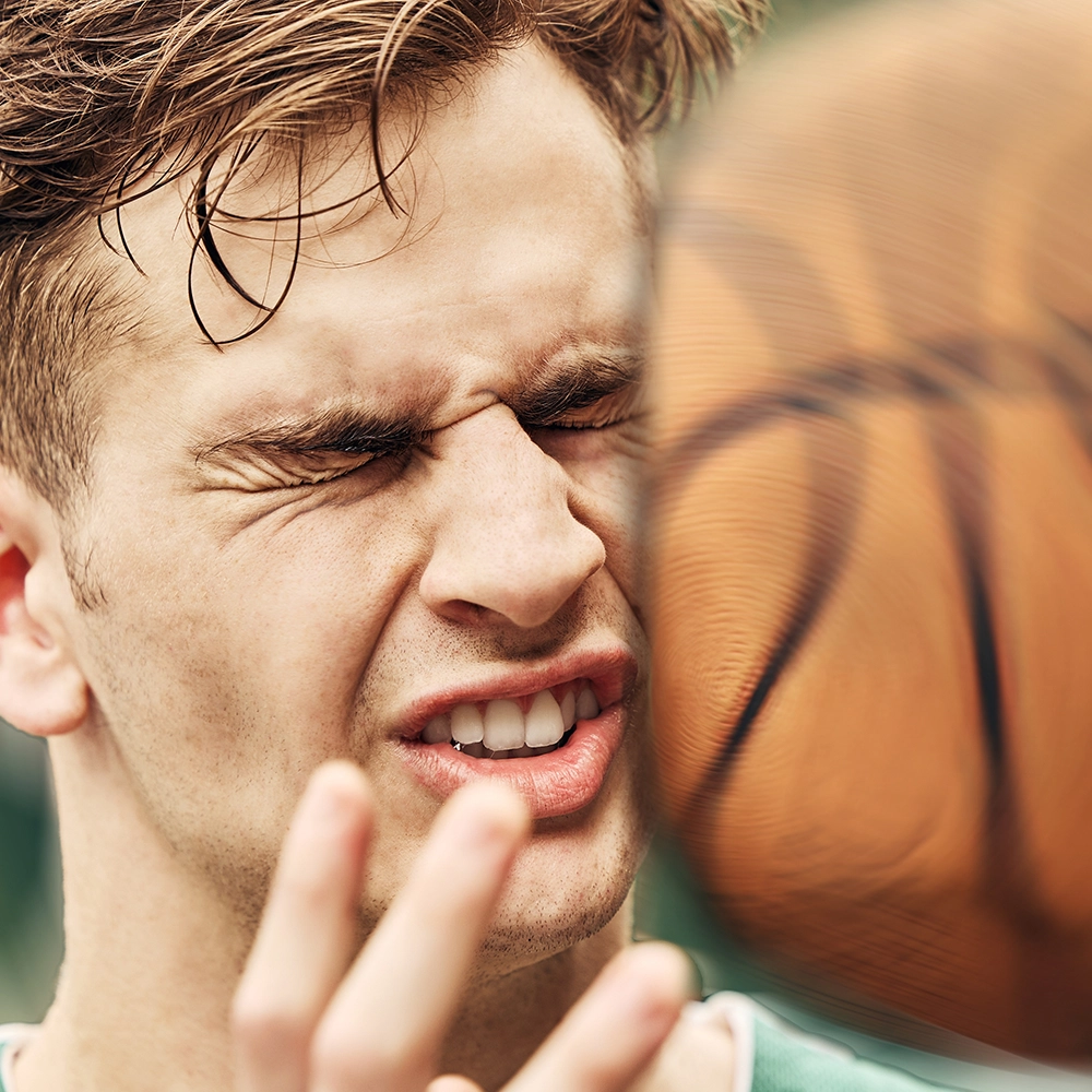 Man being struck in the face by a basketball.
