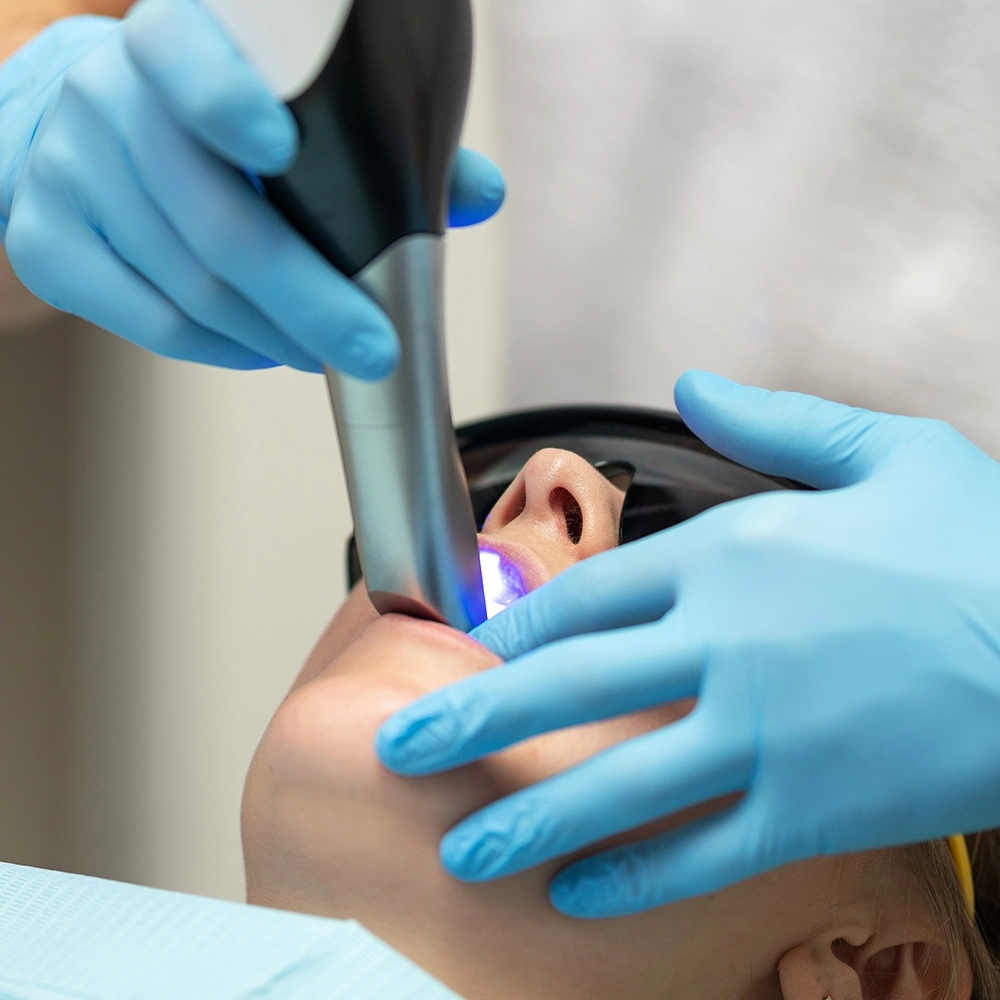Patient receiving ultraviolet light treatment on her teeth.
